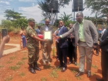 Honorable Minister and District leadership receiving a certificate of completion from the UPDF Engineering brigade
